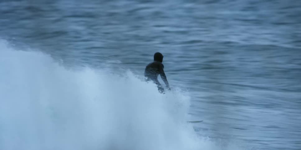 A surfer rides a fast flowing wave towards the shore