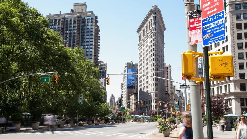People crossing the street and vehicles passing by downtown on a sunny day