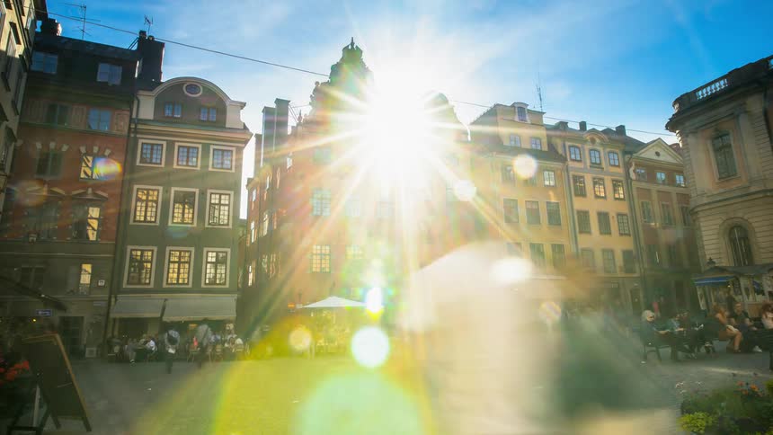 People walk in a city square and visit cafes and shops