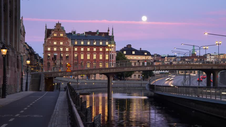 People ride bicycles and walk across a pedestrian bridge in a city