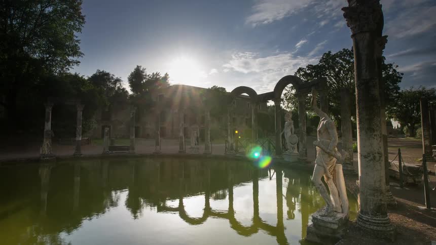 Statues near a pool of greenish water in a city