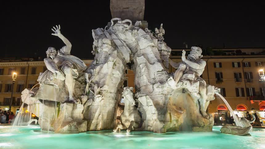 People walk near a fountain in a city