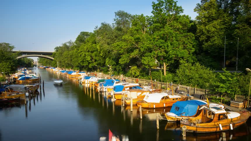 Wooden boats parked on a river as many other boats pass by