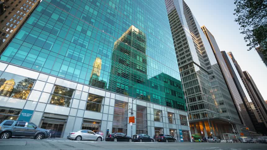 People travel and drive past the tall buildings