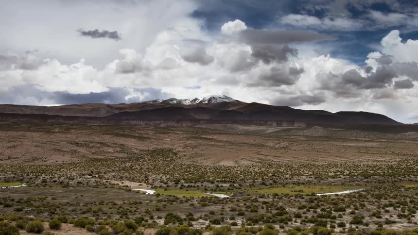 Clouds pass over an open field and mountains
