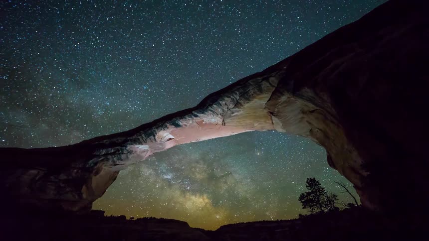 Stars pass over a rock archway