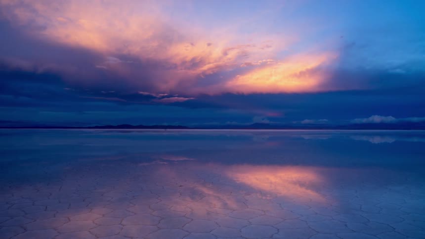 The sun sets over an icy mountain lake