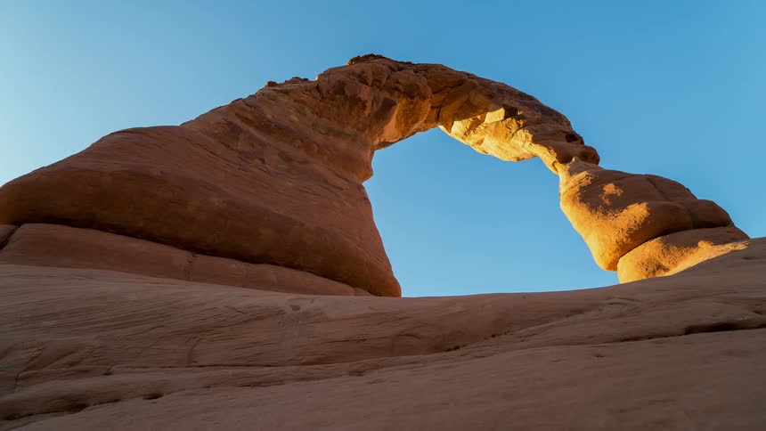 A rock archway towers overhead at sunset