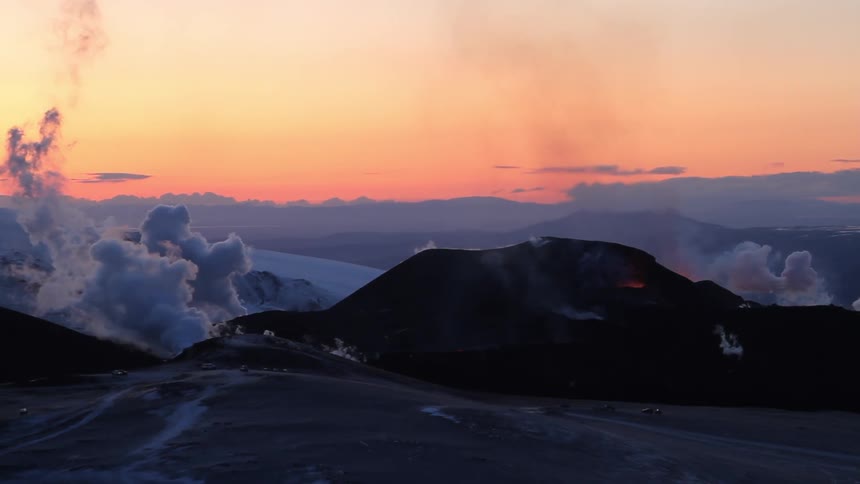 Smoke and steam are rising from a volcano at sunrise