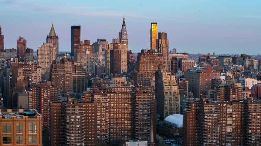 Sun setting over tall skyscrapers in a city
