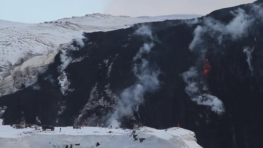 Steam is rising from fissures on a mountainside in winter