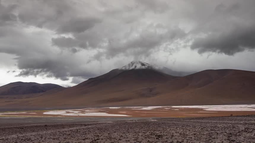 Clouds float over mountains with snow on the ground