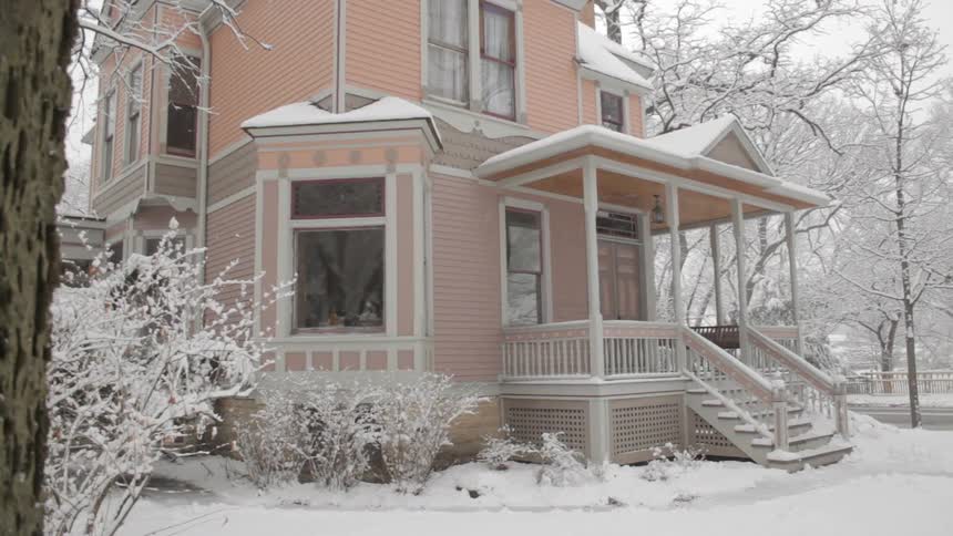 Snow falls outside of a pink house