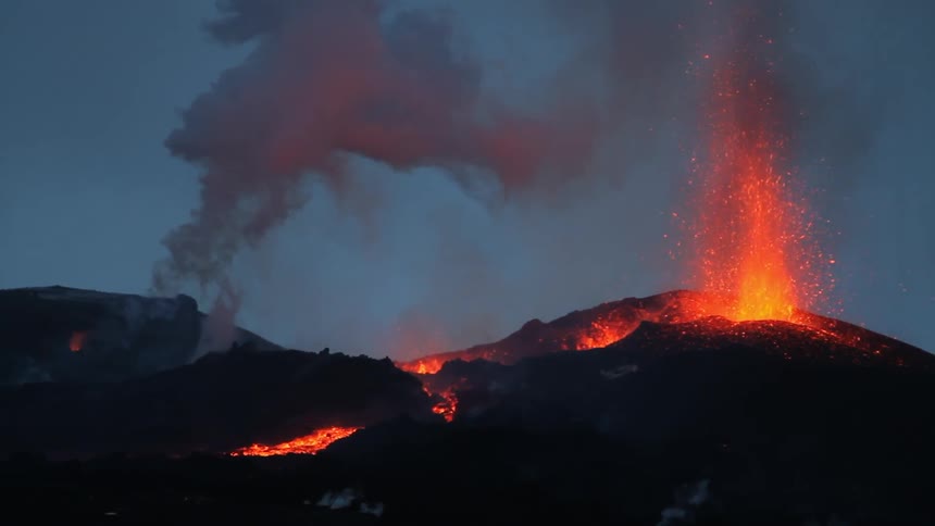 The lava is shooting up and smoking on the rocks