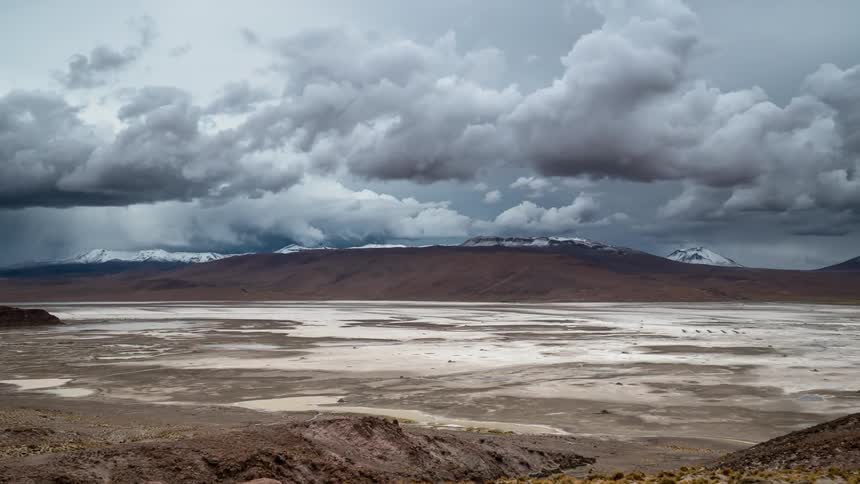 Clouds move over hills and snow capped ridge