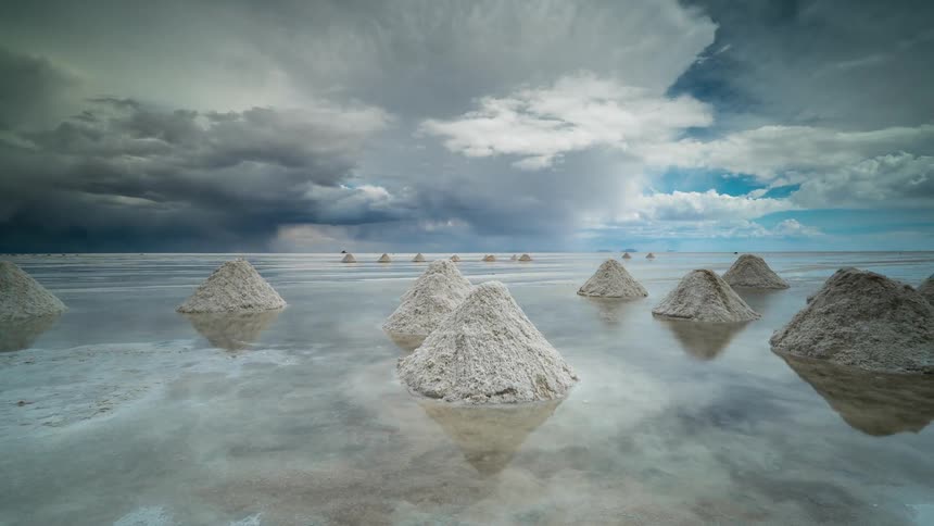 Small mounds of salt sit in the shallow water
