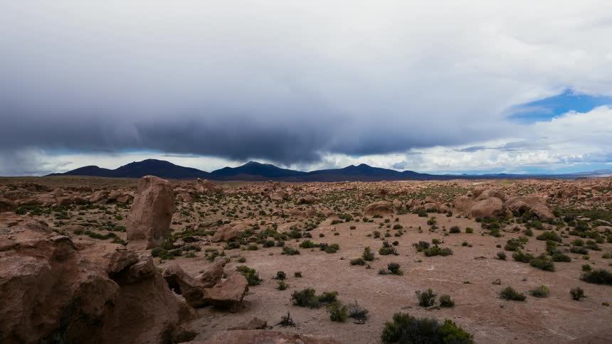 Clouds move over a desert landscape and hills