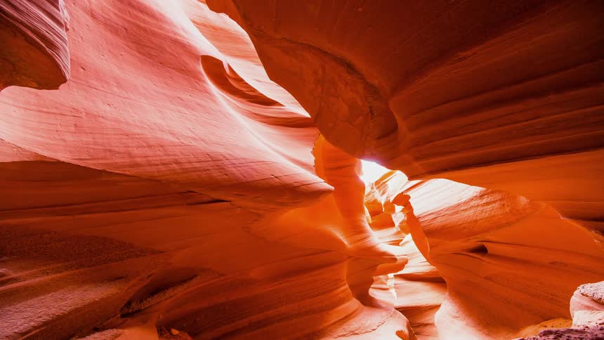The sun shines down on a curving red canyon
