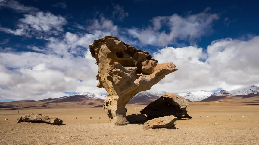 Clouds travel over a desert with a rock formation