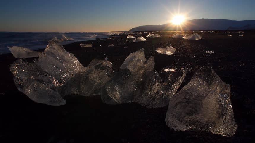 Chunks of ice sit on the beach as waves come to shore