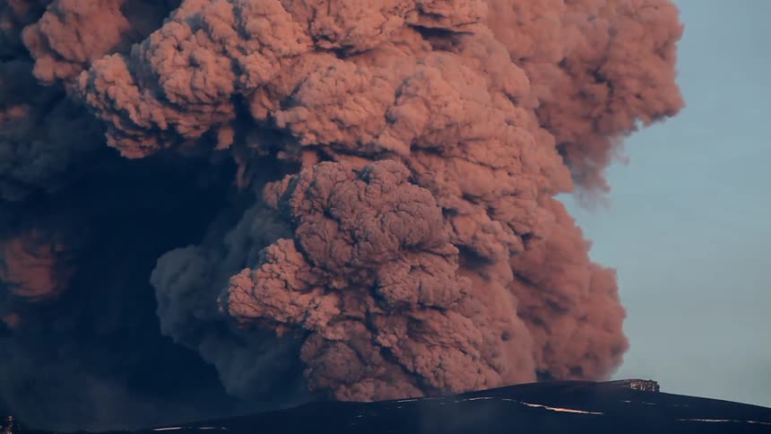 Smoke is billowing from a volcano during the day
