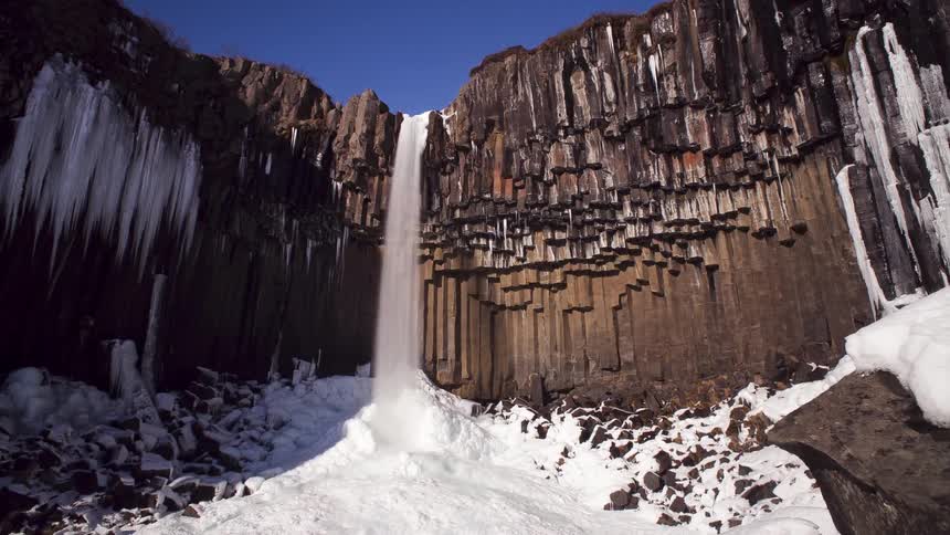 Water falls off the top of a tall cliff