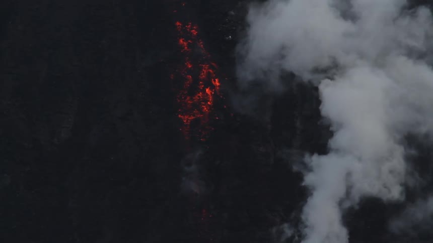 Lava glows red as it flows down the volcano