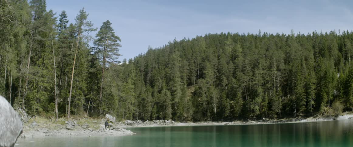 A man walks to the edge of the lake