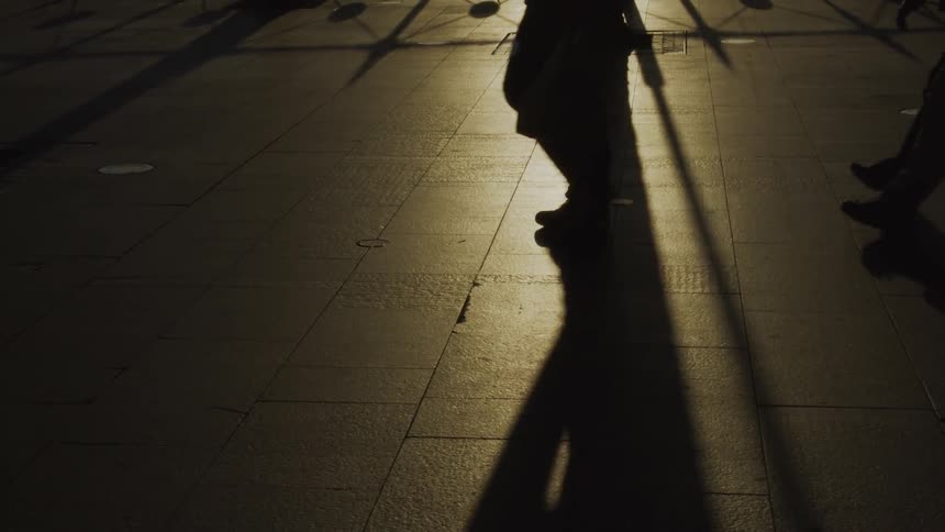 People are walking on a city boardwalk at dusk