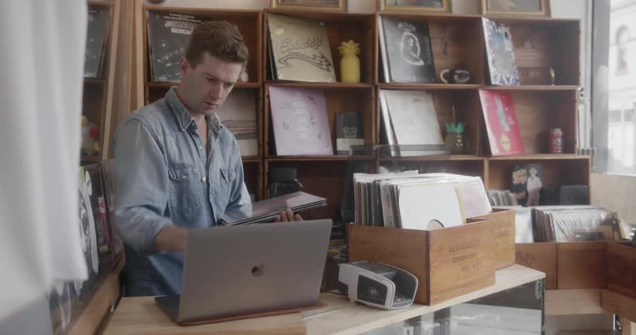 Man using his laptop to organize record albums in a shop