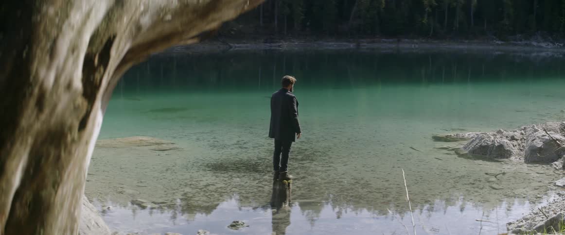 A man stands on a rock in shallow river water