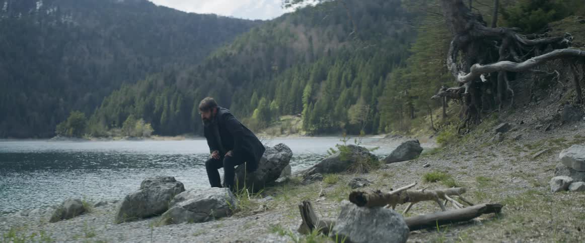 A man slowly walks towards the lake