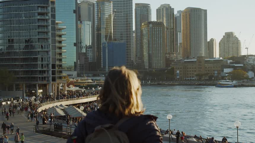 A woman overlooks onto people walking on the city pier