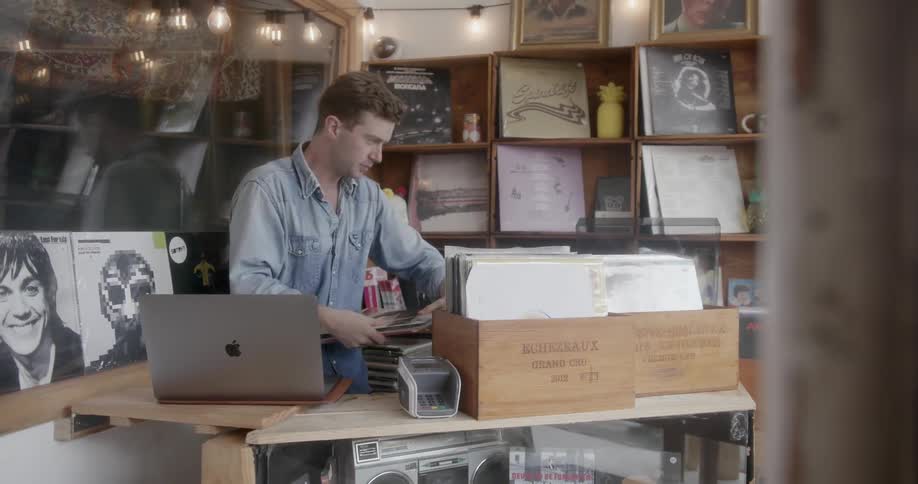 A man working in a record shop puts labels on the albums