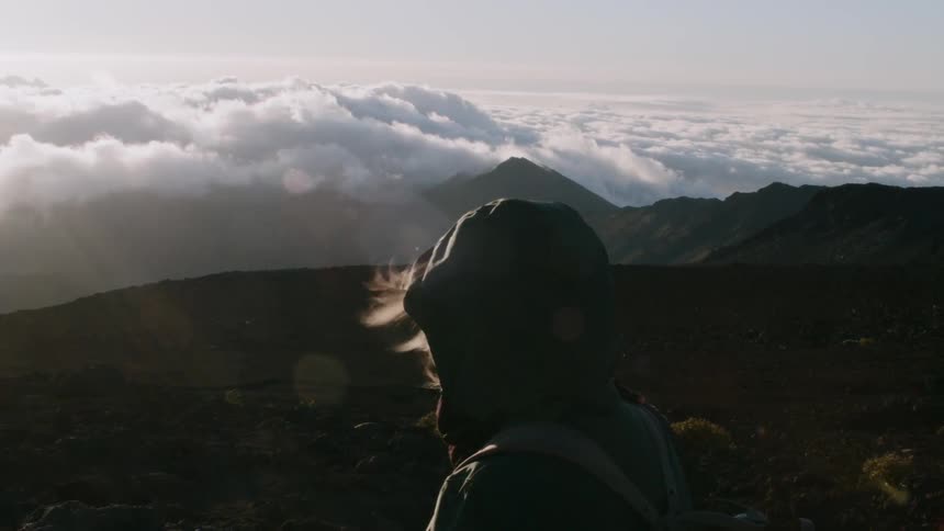 A woman stands atop a tall mountain