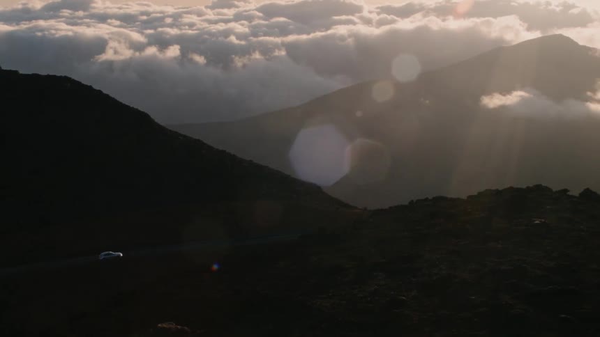 A car drives in mountains at sunset