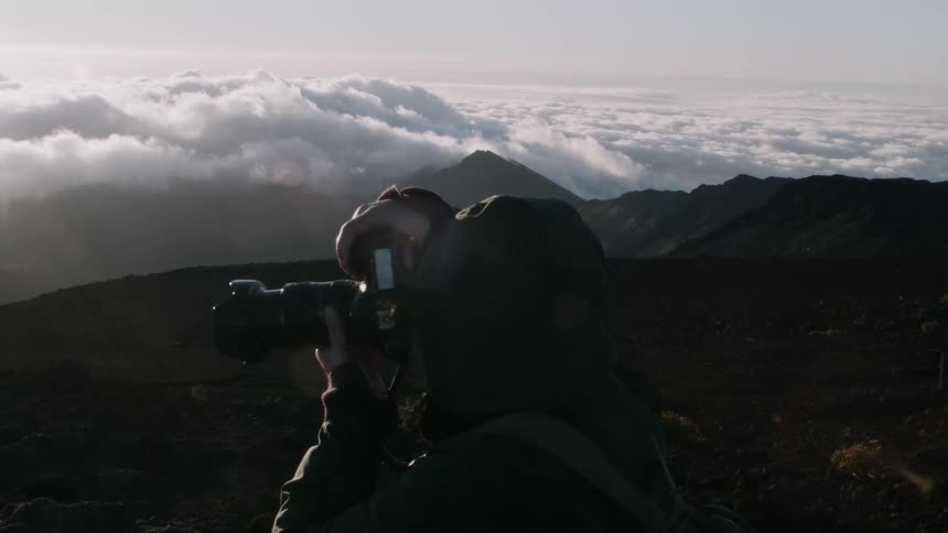 A photographer is taking a picture from a mountaintop on a cloudy day