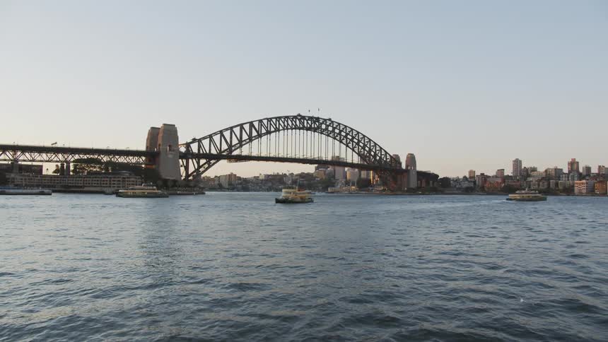 Boats are navigating a river near a city near dusk