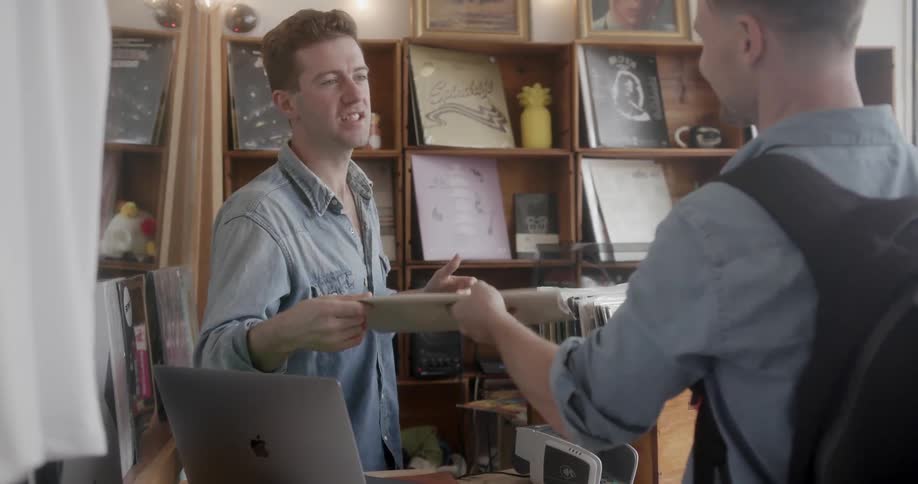 A man in a record store is interacting with a customer