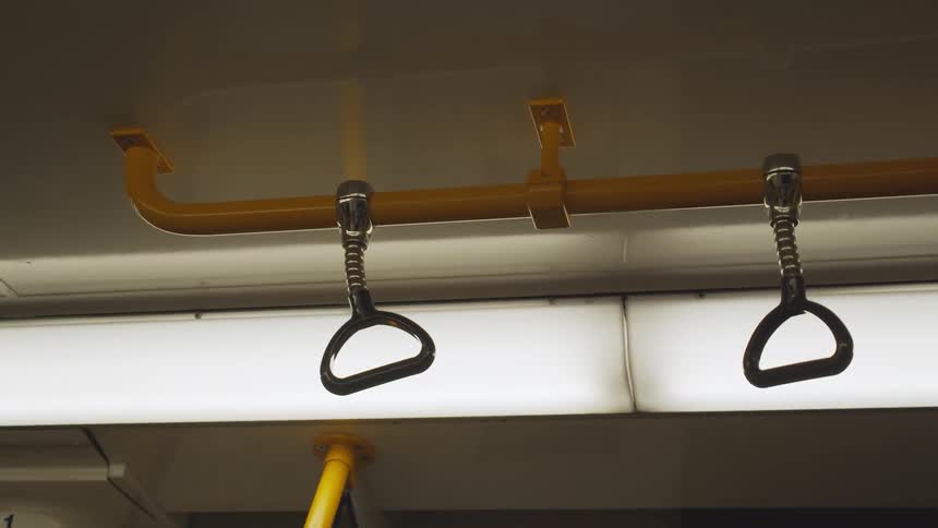 Two hooks hang from a rod on a train car ceiling