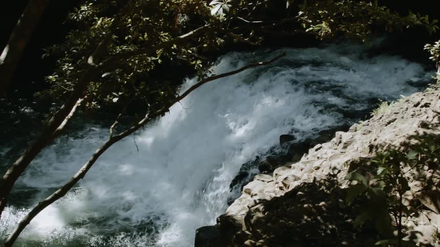 A stream is cascading over a ledge as it flows during the day