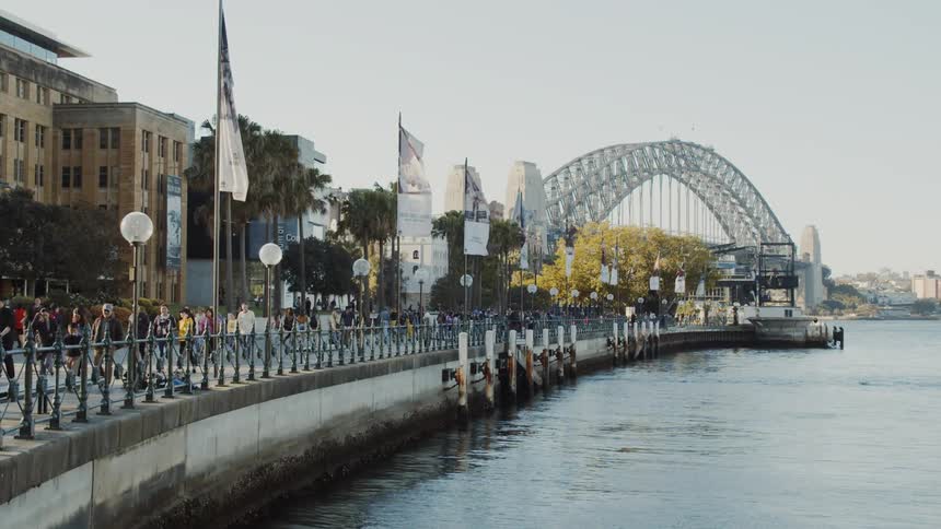 People are walking on a boardwalk near a river during the day