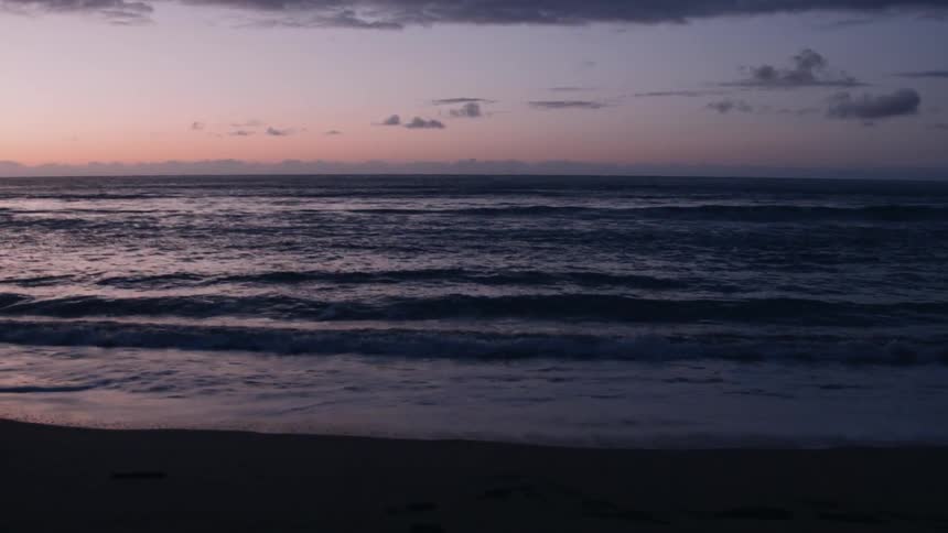 The tide is rolling onto a beach at dusk