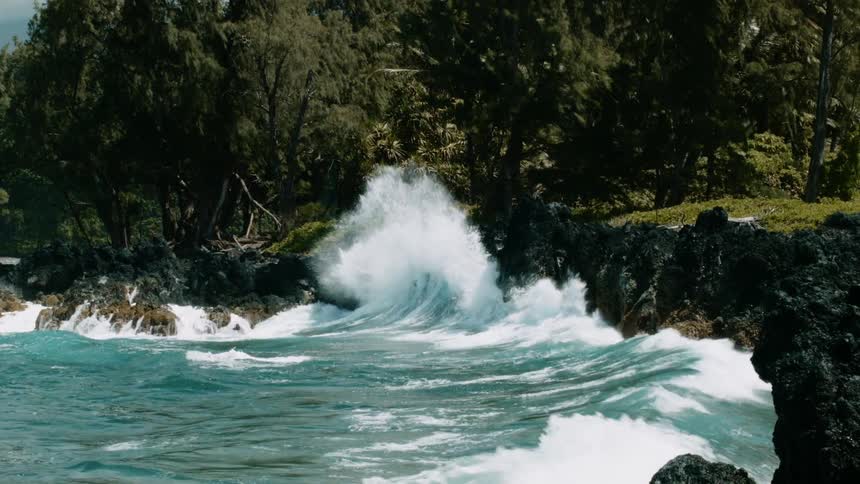 Blue-green waves and white foam splash up against the rocks