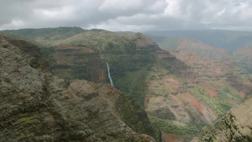 Water falls off the side of a cliff into the ravine
