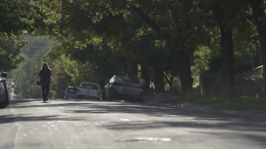 Person walking down a street with many trees