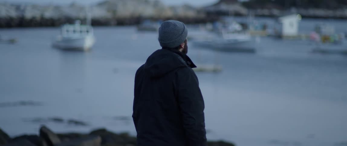 A man looks out towards docked boats on the water
