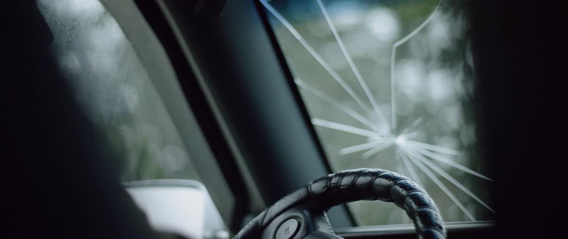 A man drives a car with a cracked windshield