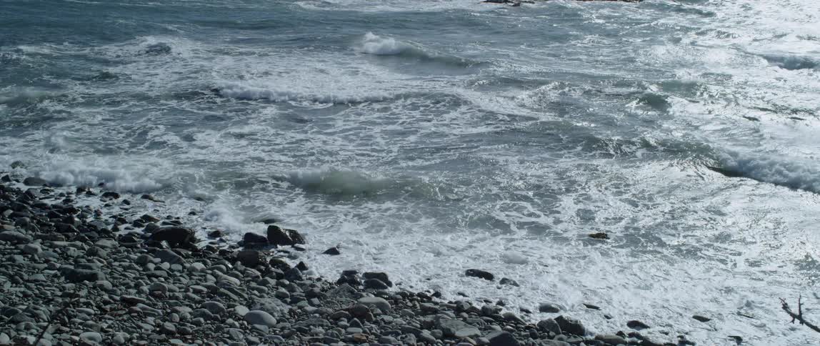 Waves are rolling onshore on a rocky beach during the day
