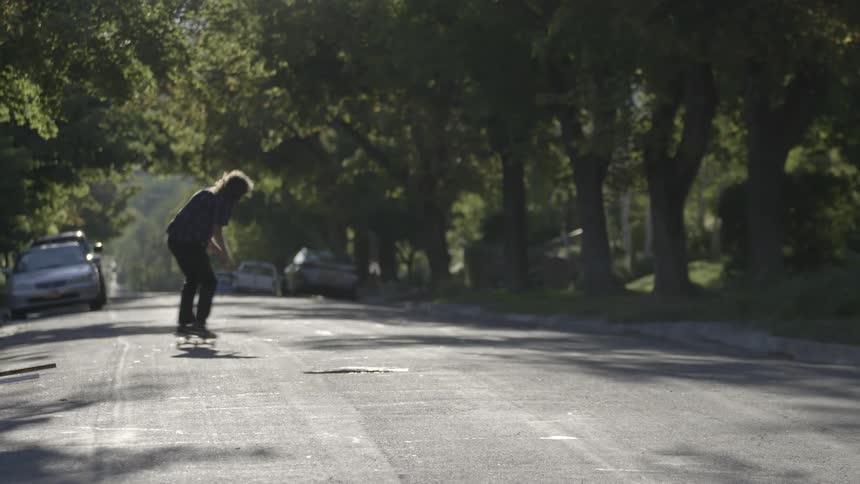 Man riding and jumping on his skateboard down a street